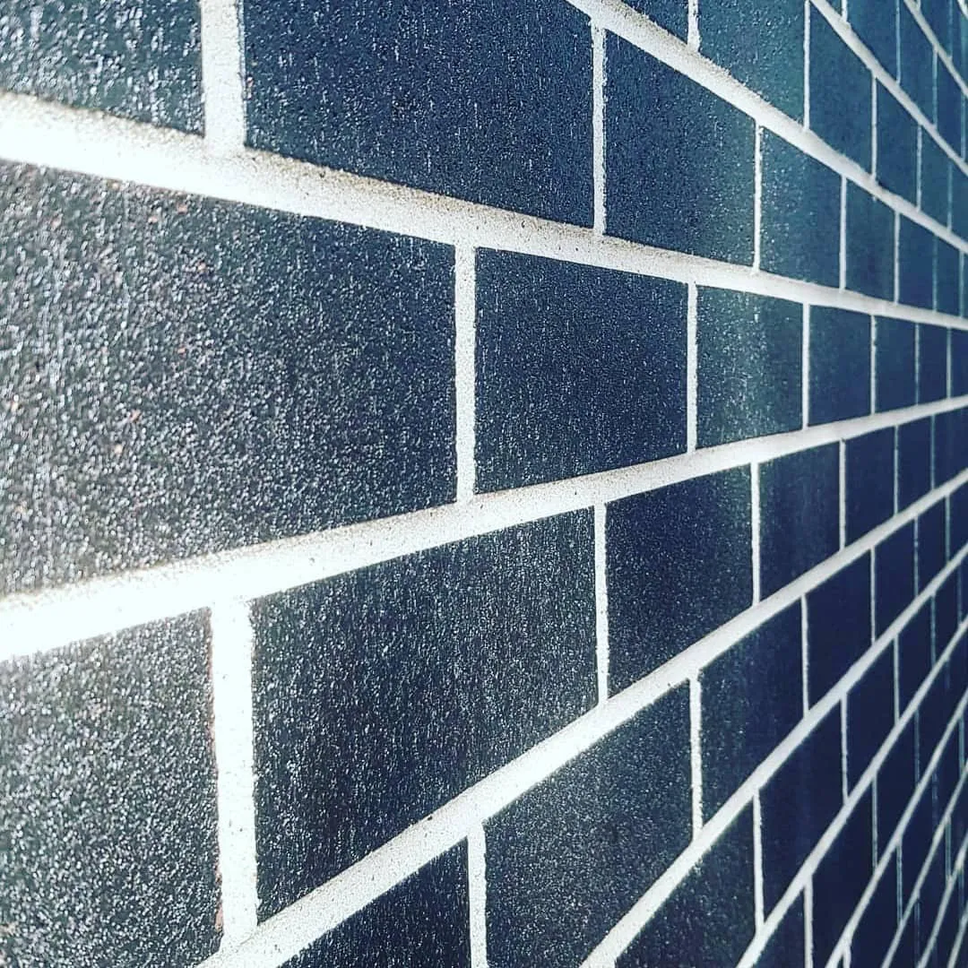 Close-up of dark glazed brickwork with crisp white mortar joints after cleaning