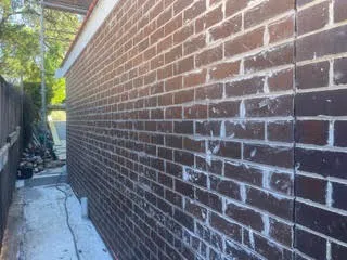 Dark brick side wall showing white cement film and mortar smear