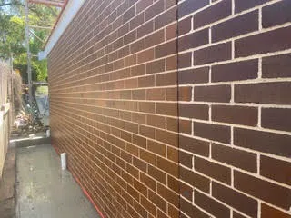 Clean red brown brick wall running alongside a concrete path