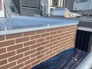 The same brick parapet wall after efflorescence removal, with the red brick and mortar colour restored
