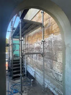 Soiled heritage sandstone archway behind scaffolding before cleaning