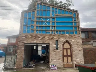 House under construction with mortar smear across the brick facade before the handover clean