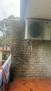 Dirty brick courtyard wall behind an air conditioning unit before cleaning
