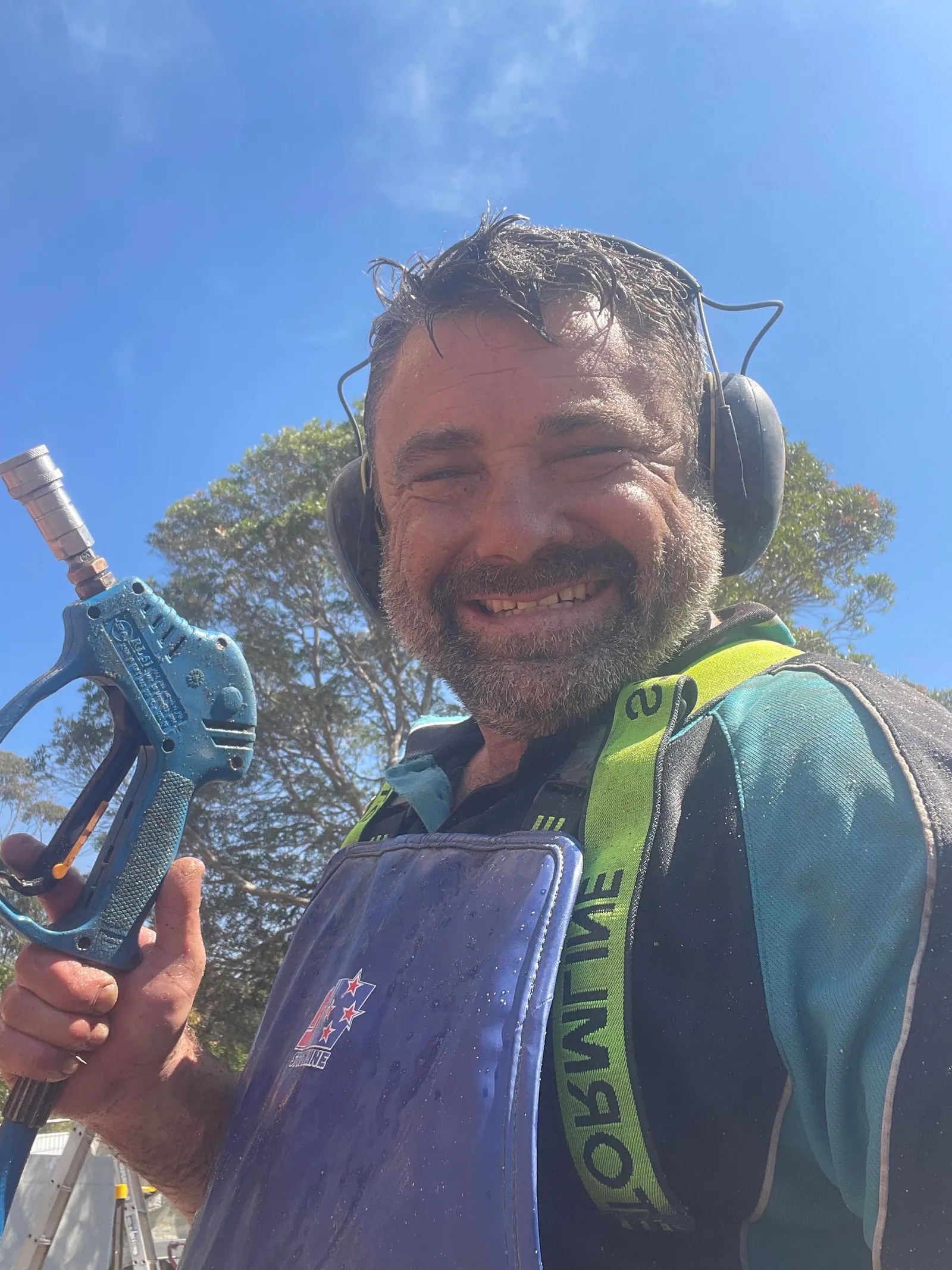 Brick Cleaning Specialists operator in hi-vis and ear protection holding a pressure cleaning wand on site